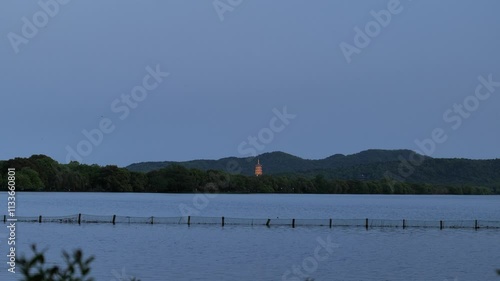 A tranquil sunset over West Lake (Xi Hu) in Hangzhou, China. The sun dips below the horizon, casting golden reflections on the rippling waters. High quality 4k footage photo