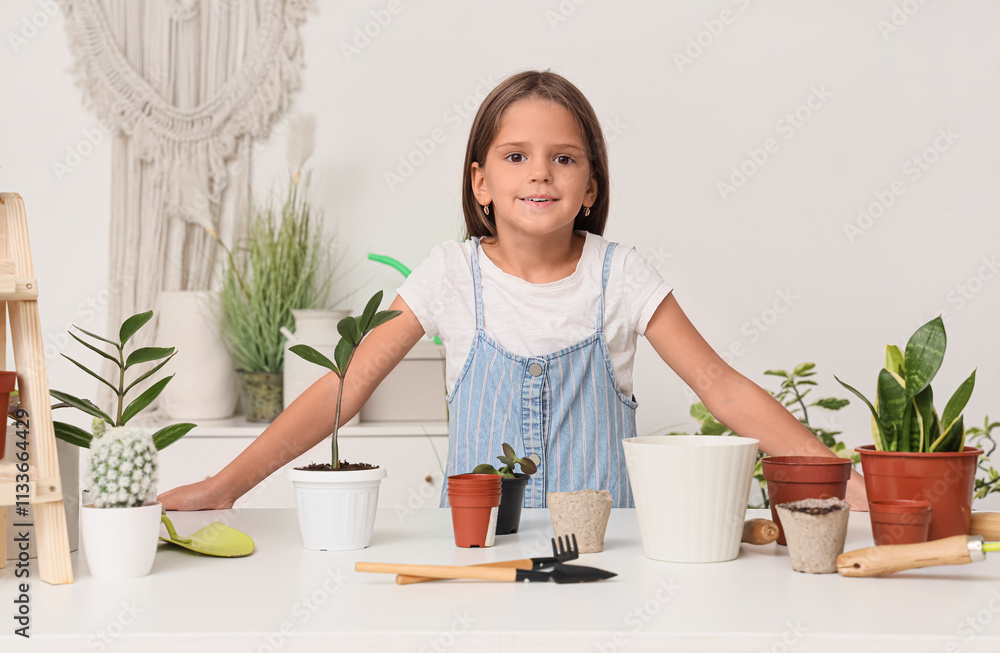 Cute little girl with plants and gardening tools in workshop Cute little girl with plants and gardening tools in workshop
