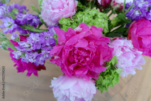 A vivid floral arrangement featuring fuchsia peonies, pale pink blossoms, purple blooms, and fresh green accents, exuding elegance and the beauty of nature’s vibrant colors.