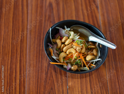 Cashew nuts in black cup placed on wooden table with copy space for use