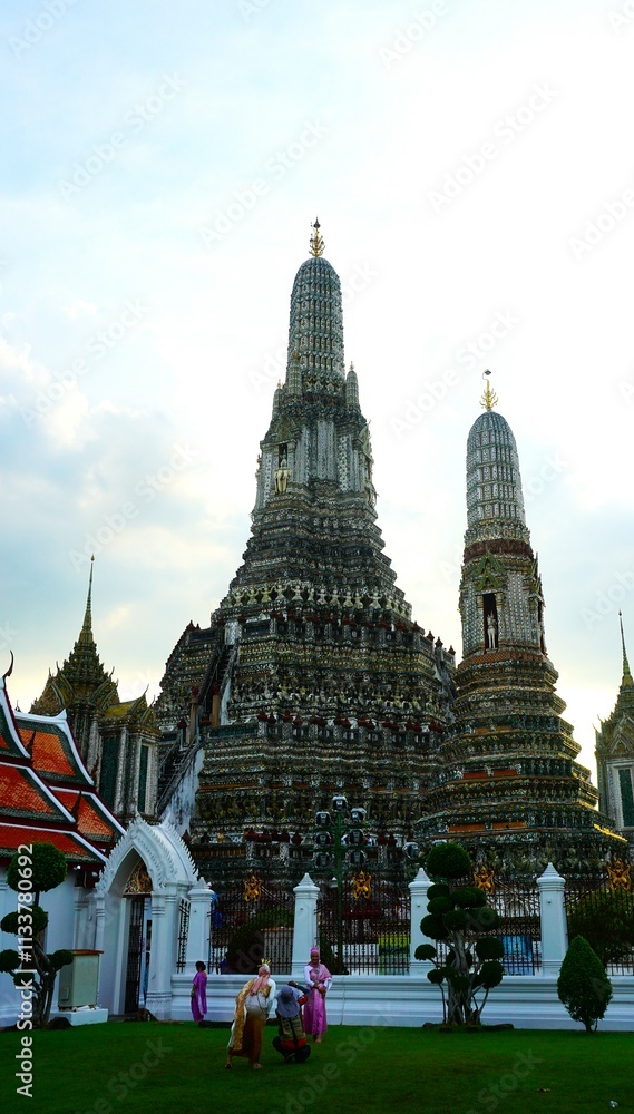 Fototapeta premium Świątynia Świtu Wat Arun w Bangkoku, znana z niezwykłych wież pokrytych kolorowymi mozaikami. Ikoniczny zabytek Tajlandii nad brzegiem rzeki Chao Phraya, emanujący duchowym spokojem.