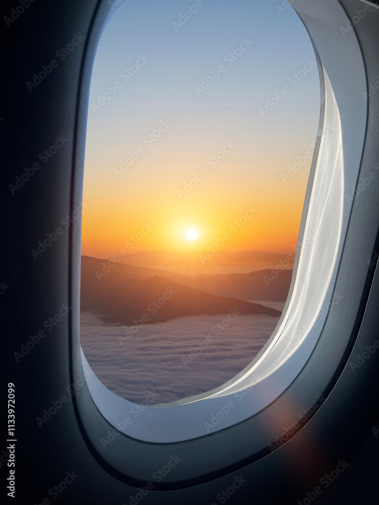 Airplane flying low over foggy mountains, view from plane window of plane wing and sky sunrise Airplane flying low over foggy mountains, view from plane window of plane wing and sky sunrise