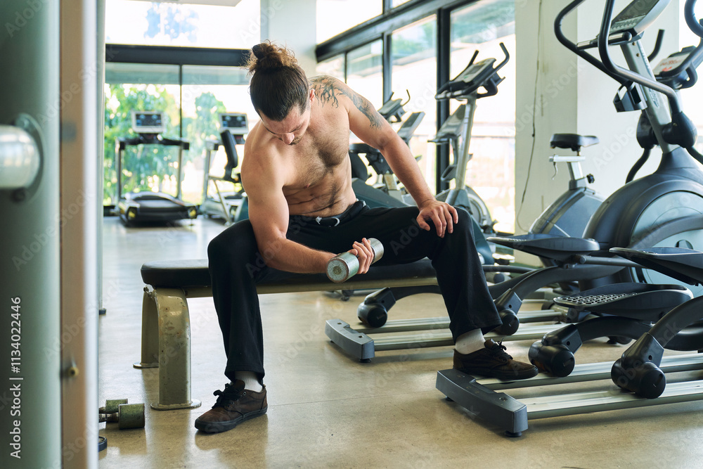 A Caucasian handsome shirtless sportsman show perfect body and his muscular working out weight with iron drumbrel in fitness gym. A Caucasian handsome shirtless sportsman show perfect body and his muscular working out weight with iron drumbrel in fitness gym.