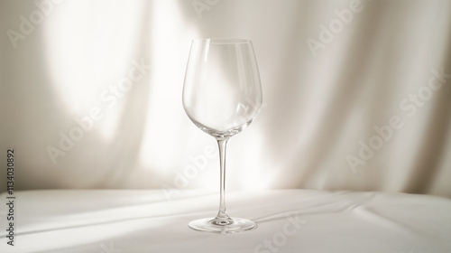 Minimalist clear wine glass on a white table with soft shadow play, ideal for lifestyle or product website banners and headers