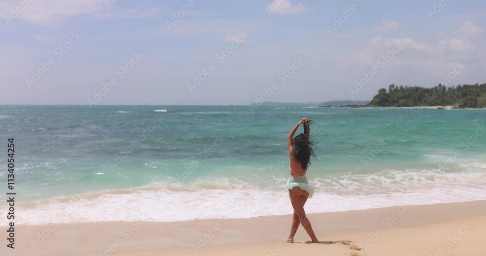 A young woman in a bikini walking along the sandy beach, posing and enjoying the ocean breeze under a sunny sky. Ideal for summer, travel, freedom, and lifestyle projects. A young woman in a bikini walking along the sandy beach, posing and enjoying the ocean breeze under a sunny sky. Ideal for summer, travel, freedom, and lifestyle projects.