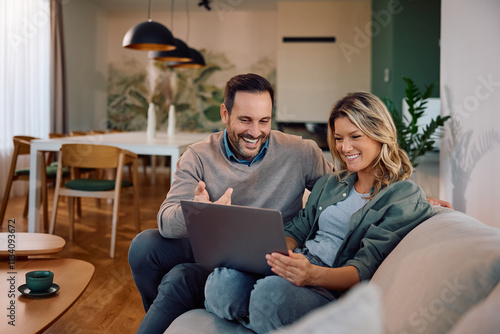 Photography Happy couple surfing the net on laptop while relaxing in their living room