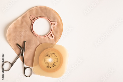 Preparing to change an ostomy bag and adhesive barrier with scissors on a white background and copy space.