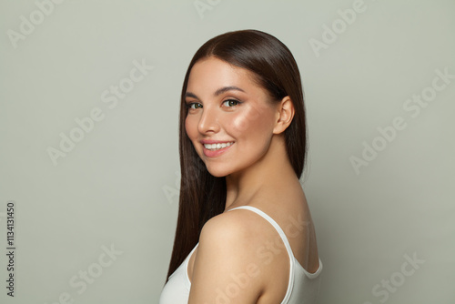 Smiling brunette woman with glowing skin, subtle makeup and a gentle smile. Young model posing, portrait