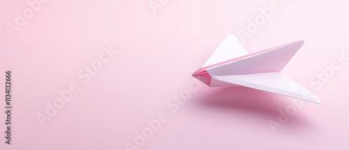 A simple white paper airplane on a soft pink background, symbolizing creativity and playfulness.