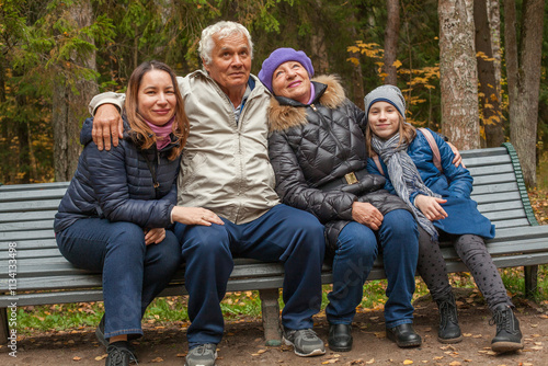 Happy family sitting on the bench in autumn park