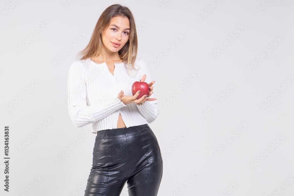 Attractive brunette young woman holding a red apple and standing on a white background. Copy space Attractive brunette young woman holding a red apple and standing on a white background. Copy space