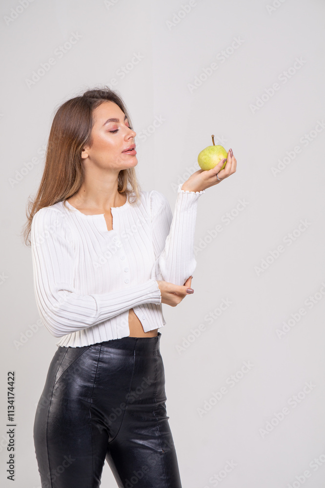 Attractive brunette young woman holding a yellow pear and standing on a white background. Copy space Attractive brunette young woman holding a yellow pear and standing on a white background. Copy space