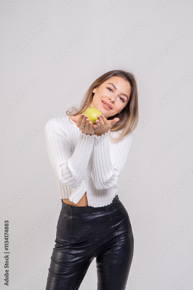 Attractive brunette young woman holding a yellow pear and standing on a white background. Copy space Attractive brunette young woman holding a yellow pear and standing on a white background. Copy space