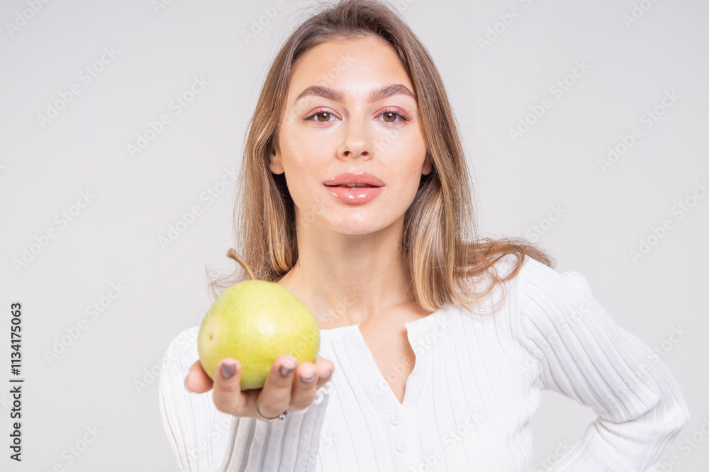 Close-up portrait of attractive brunette young woman holding a yellow pear on a white background. Copy space Close-up portrait of attractive brunette young woman holding a yellow pear on a white background. Copy space