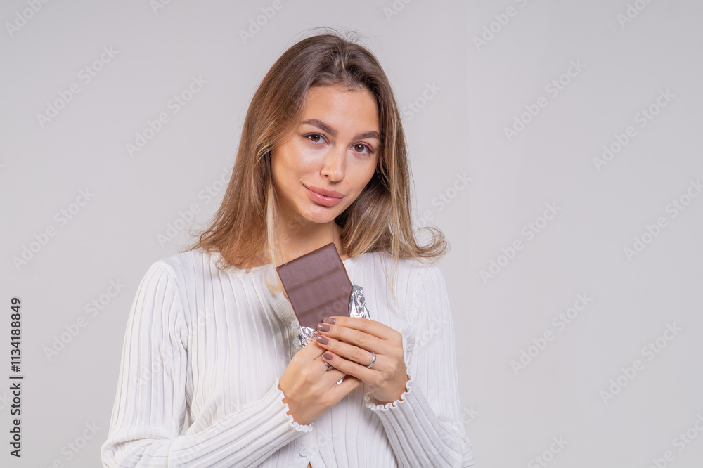Beautiful young smiling girl with a chocolate bar on a white background, copy space. Close-up portrait Beautiful young smiling girl with a chocolate bar on a white background, copy space. Close-up portrait