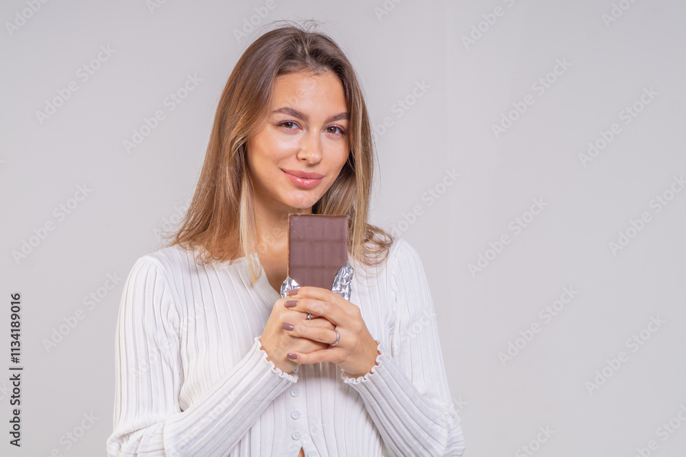 Beautiful young smiling girl with a chocolate bar on a white background, copy space. Close-up portrait Beautiful young smiling girl with a chocolate bar on a white background, copy space. Close-up portrait