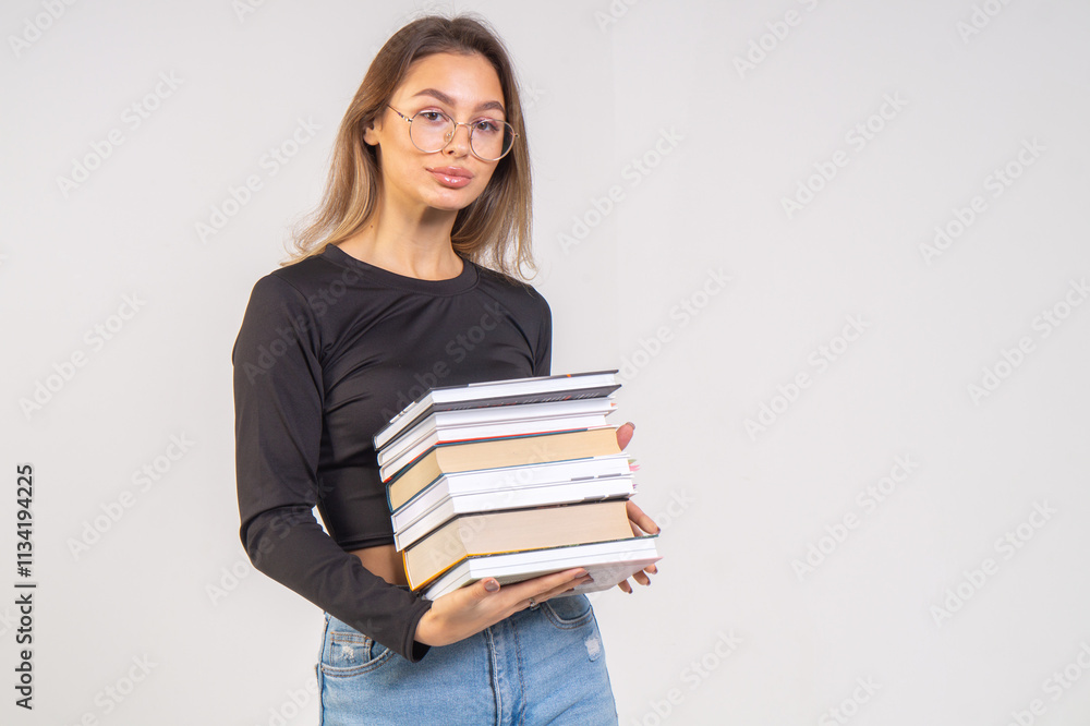 Young cute smiling girl with a stack of books on a white background. Copy space Young cute smiling girl with a stack of books on a white background. Copy space