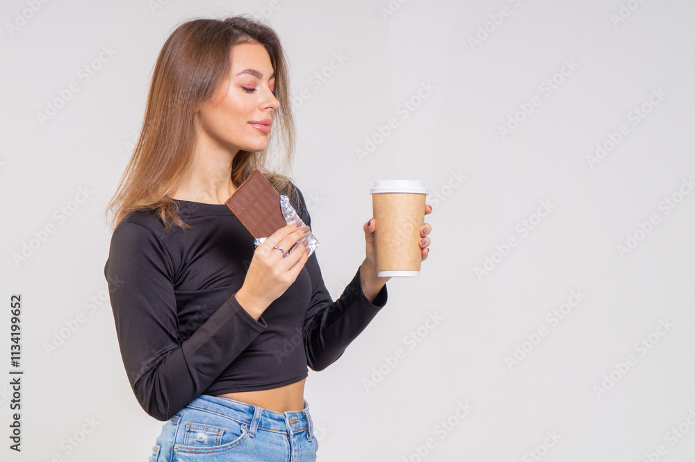 Attractive brunette young woman holding a cofee cup and chocolate on a white background. Copy space Attractive brunette young woman holding a cofee cup and chocolate on a white background. Copy space