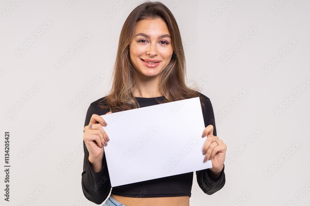 Beautiful young smiling brunette with a sheet of paper A4 close-up on a white background Beautiful young smiling brunette with a sheet of paper A4 close-up on a white background