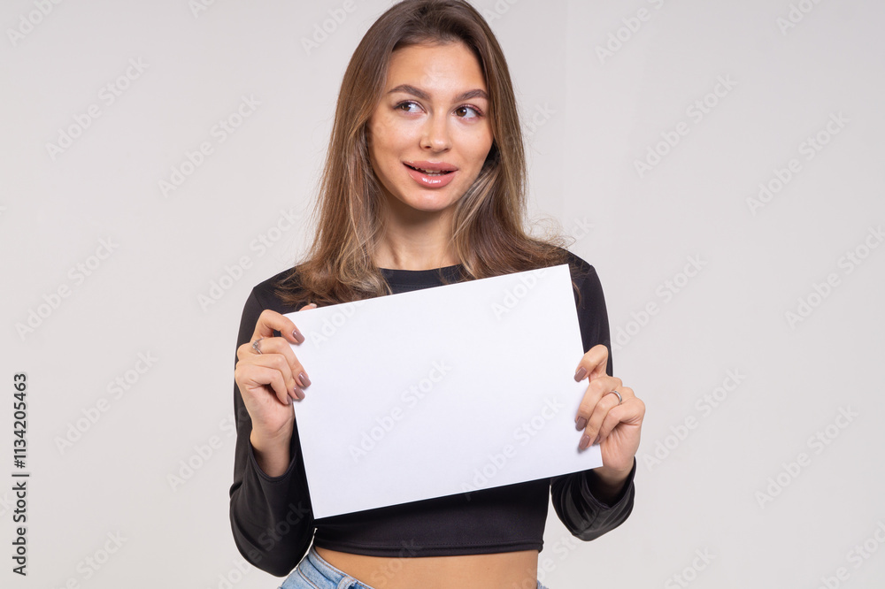 Beautiful young smiling brunette with a sheet of paper A4 close-up on a white background Beautiful young smiling brunette with a sheet of paper A4 close-up on a white background