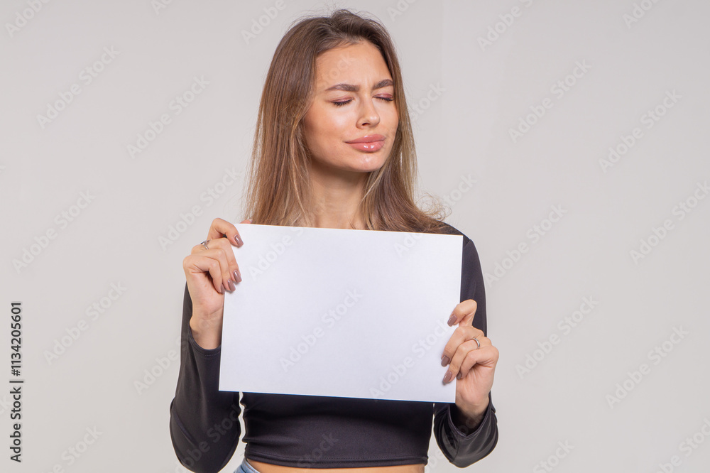 Beautiful young smiling brunette with a sheet of paper A4 close-up on a white background Beautiful young smiling brunette with a sheet of paper A4 close-up on a white background