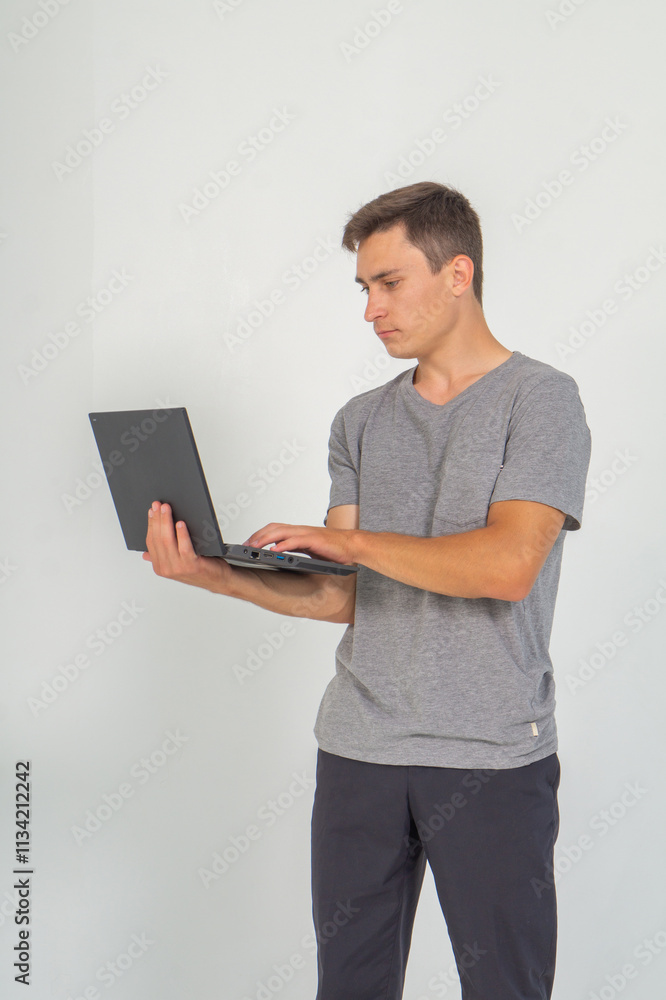 Young man working on laptop standing on a white background Young man working on laptop standing on a white background