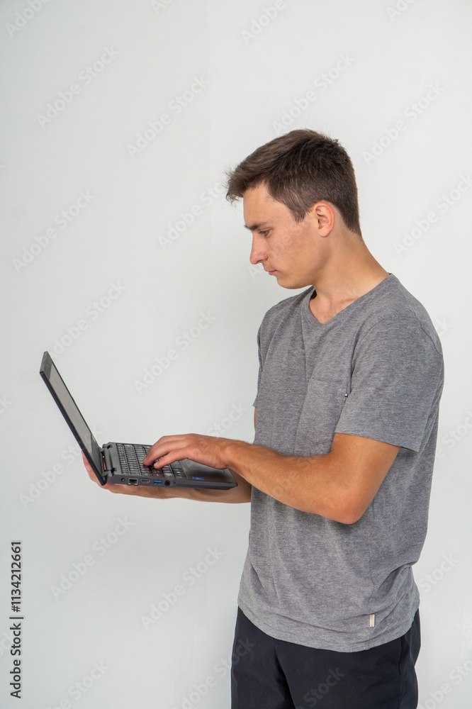 Young man working on laptop standing on a white background Young man working on laptop standing on a white background