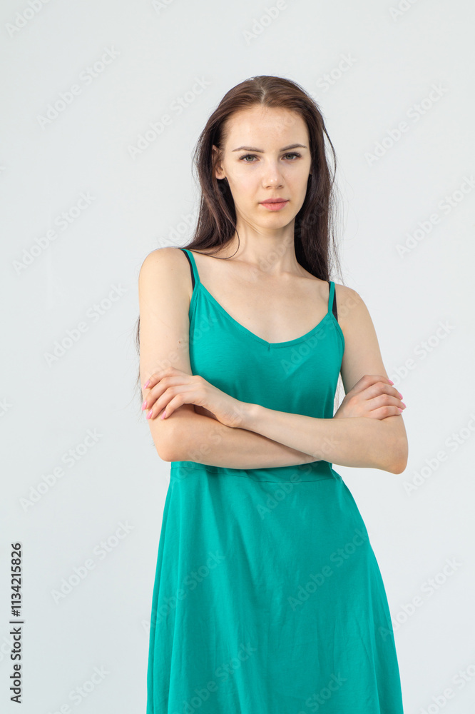 Young attractive skinny girl in green short dress posing standing on white background Young attractive skinny girl in green short dress posing standing on white background