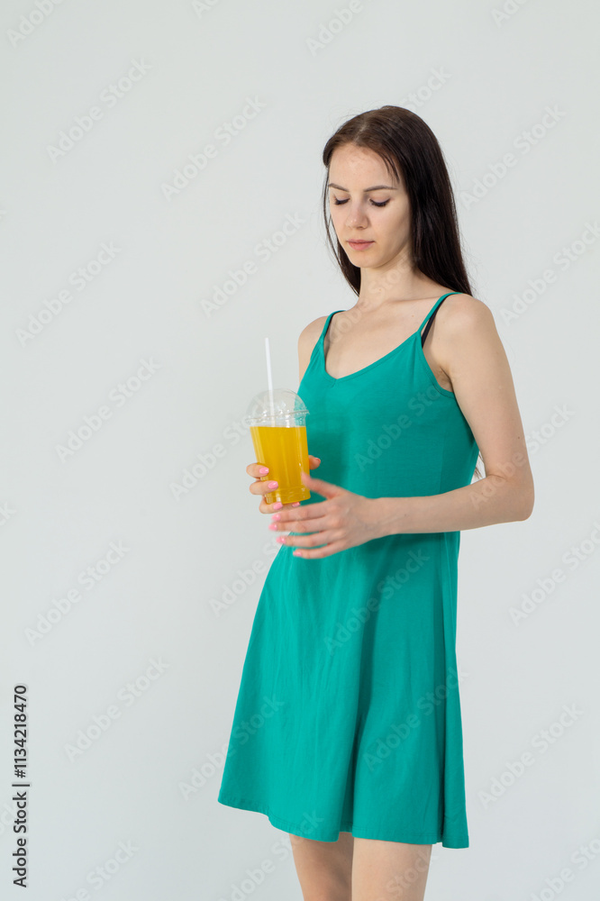 Young attractive girl in a short green dress with a cocktail in her hands on a white background Young attractive girl in a short green dress with a cocktail in her hands on a white background