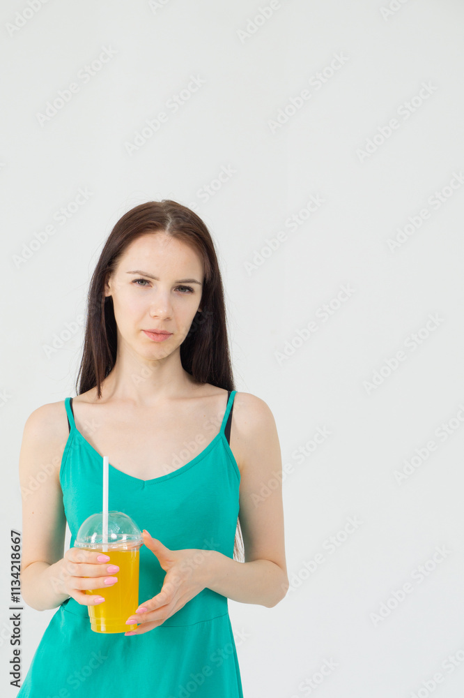 Young attractive girl in a short green dress with a cocktail in her hands on a white background Young attractive girl in a short green dress with a cocktail in her hands on a white background