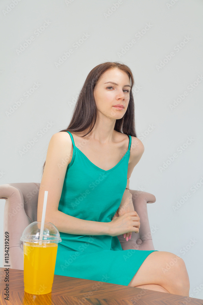 Young attractive girl in a short green dress with a cocktail in her hands on a white background Young attractive girl in a short green dress with a cocktail in her hands on a white background