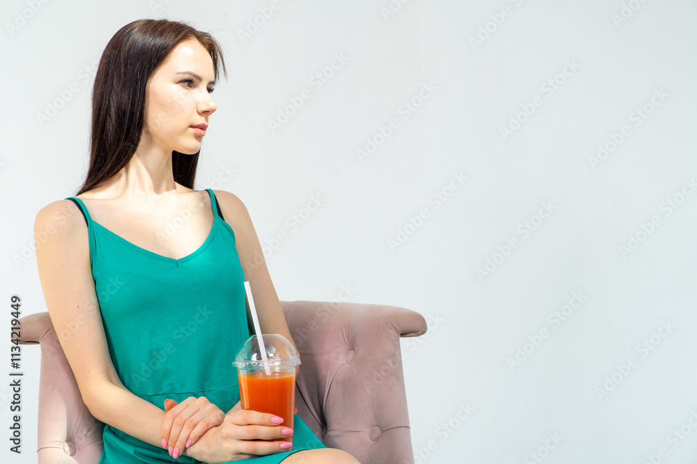 Young attractive girl in a short green dress with a cocktail in her hands on a white background Young attractive girl in a short green dress with a cocktail in her hands on a white background