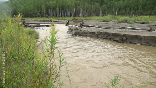 An ecological disaster. A river polluted by gold miners flows past the road.