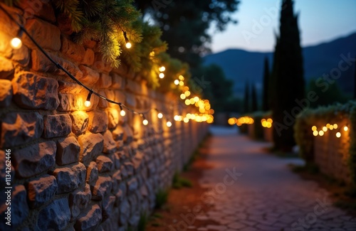 Rustic Sardinian stone wall glows with twinkling Christmas lights at dusk. Winter wonderland scene. Pathway leads through cypress trees. Festive ambiance. Holiday decorations. Cozy atmosphere. photo