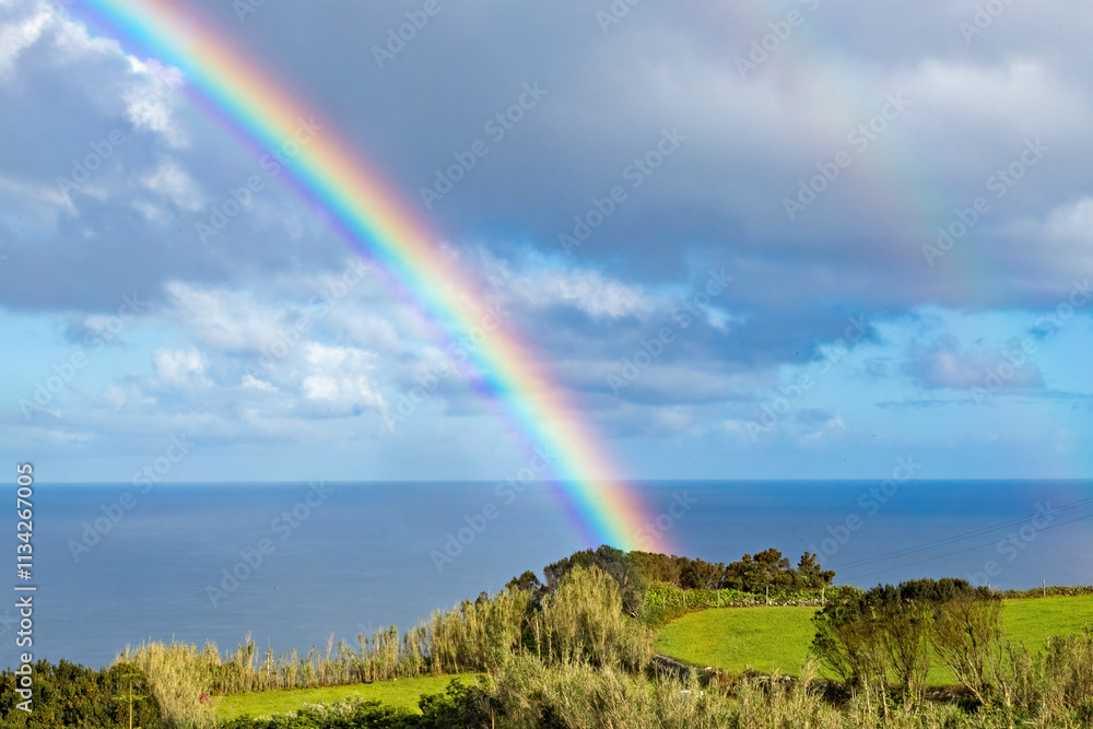 Breathtaking view of the amall village and lighthouse at São Jorge island in Azores with huge rainbow in the sky Portugal Breathtaking view of the amall village and lighthouse at São Jorge island in Azores with huge rainbow in the sky Portugal