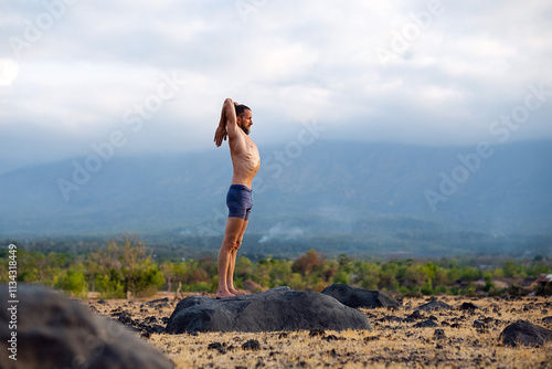 Man Practicing Yoga Meditation Outdoors in Nature with Mountain View.