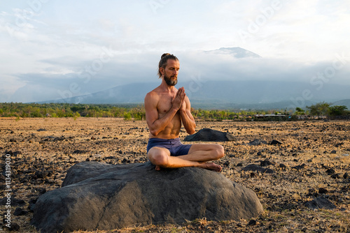 Man Practicing Yoga Meditation Outdoors in Nature with Mountain View.