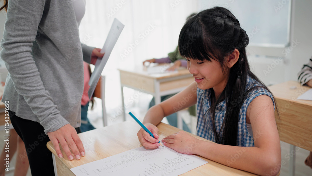 Elementary school students are sitting in the classroom at school and doing final exams in mathematics Elementary school students are sitting in the classroom at school and doing final exams in mathematics