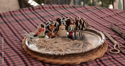 Sill life on vintage metal tray holding pinecones, decorative figures, and strands of string ready for a fun holiday craft project. This festive DIY activity brings joy to the season.