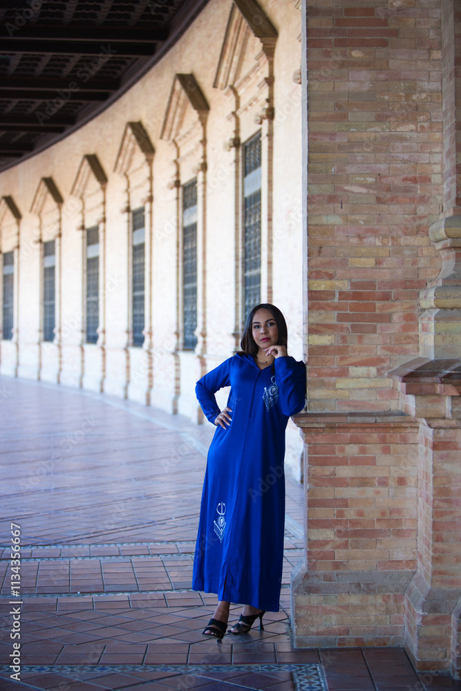 moroccan woman brunette, young and beautiful, dressed in blue abaya, typical clothes of arab woman. The woman is in the square of Spain in Seville under the arches and columns. Travel concept. moroccan woman brunette, young and beautiful, dressed in blue abaya, typical clothes of arab woman. The woman is in the square of Spain in Seville under the arches and columns. Travel concept.