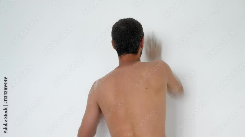 In his new house, a man works hard cleaning the white walls, shirtless and sweating due to the hot summer day. In his new house, a man works hard cleaning the white walls, shirtless and sweating due to the hot summer day.