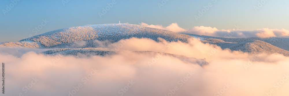 Eastern Sudetes, View of snowy mountain range in fog from hiking trail during winter hike in mountains, viewpoint of wide winter landscape in mountains at sunset.