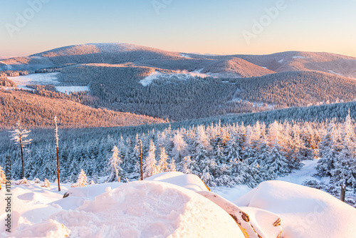 Eastern Sudetes, View of snowy mountain range from hiking trail during winter hike in the mountains, viewpoint of wide winter landscape in the mountains at sunset.