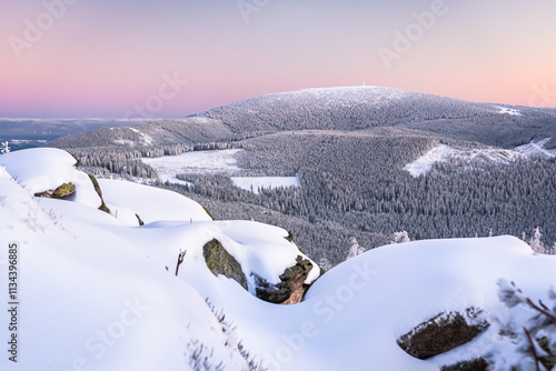 Eastern Sudetes, View of snowy mountain range from hiking trail during winter hike in the mountains, viewpoint of wide winter landscape in the mountains at sunset.