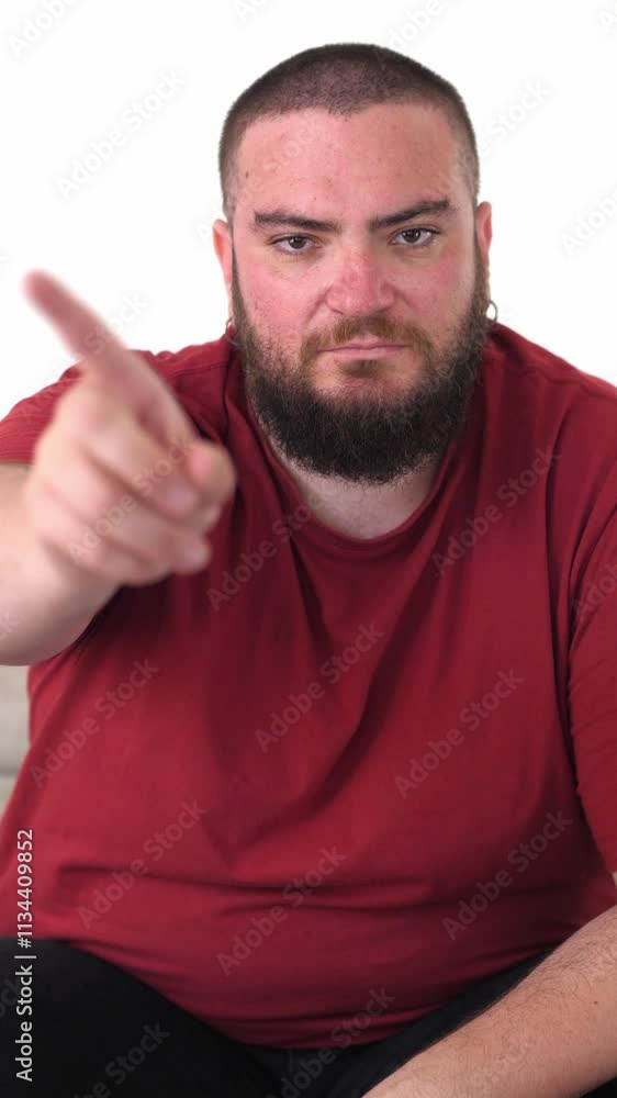 Vertical: The young man shakes his finger in disagreement, expressing his disapproval of something, as his facial expression shows clear discontent. Vertical: The young man shakes his finger in disagreement, expressing his disapproval of something, as his facial expression shows clear discontent.