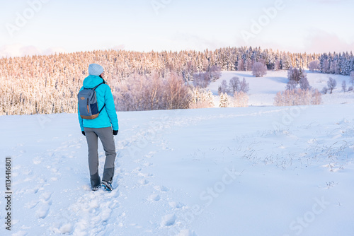 Obraz na płótnie Eastern Sudetes, Young woman on a mountain snow-covered trail, hiking in the white snow and viewing snow-covered hills, winter landscape in the mountains. w salonie