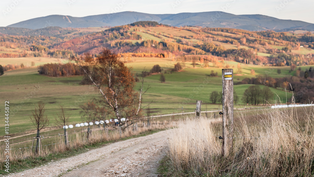 Czech Republic, Stribrnice, mountain landscape view from hiking trail, gravel road. Autumn panorama of hills and fields in late evening.