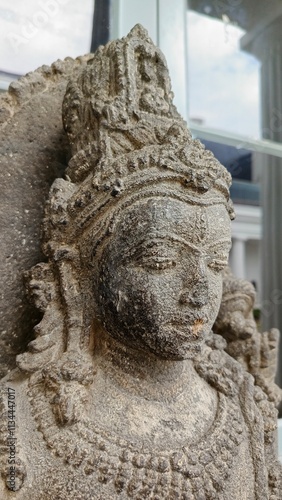 Close-up of a detailed stone statue of a serene Hindu deity, showcasing intricate carvings and textures