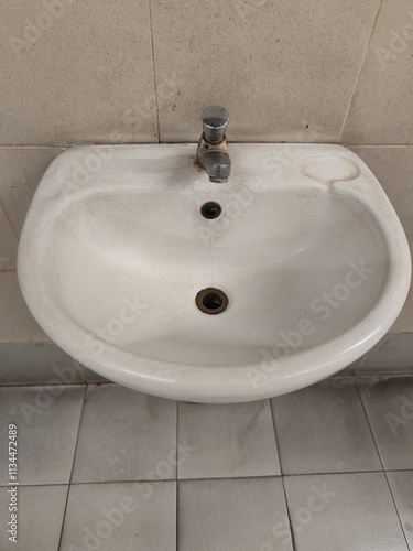 A white porcelain sink is installed on a ceramic wall