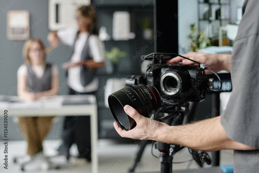Medium close up of unrecognizable operators hands holding massive professional lens